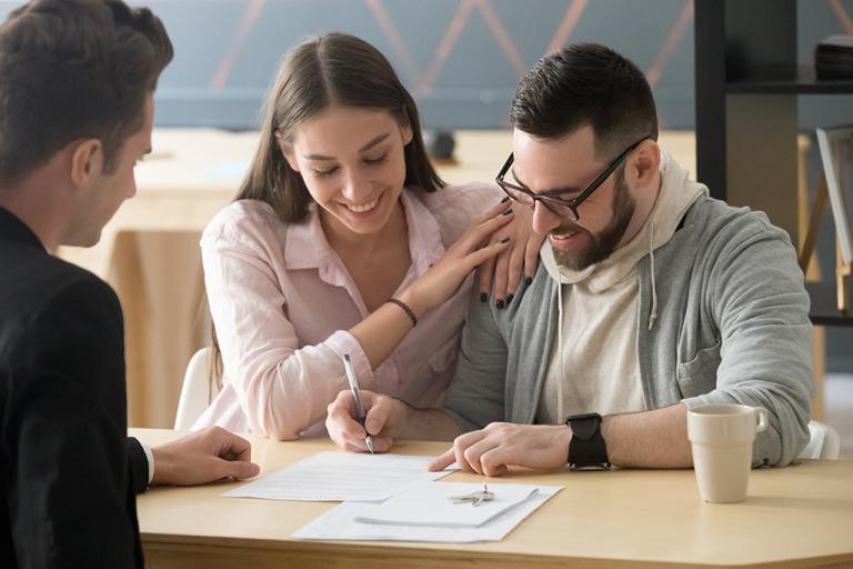 A couple signs paperwork to buy a house