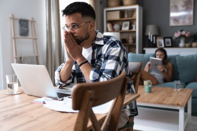 Young man at computer stressed about gambling debt