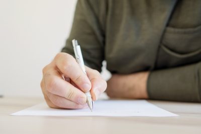 Man drafting a debt settlement letter with pen and paper